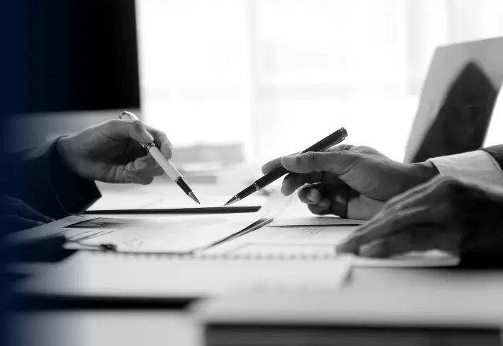 photo of two sets of hands holding pens and gesturing at documents